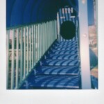 Color Polaroid of blue stairs and a tunnel that are part of playground equipment
