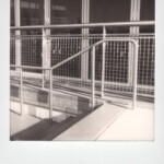 Black and white Polaroid of a stairs, railing and windows